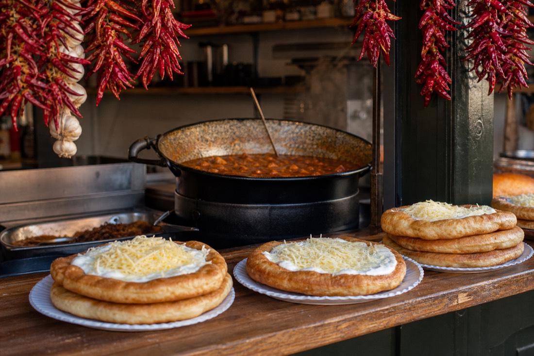 Golden langos with sour cream and cheese at a Budapest market stall, one of the tasters on the market-to-tavern food tour